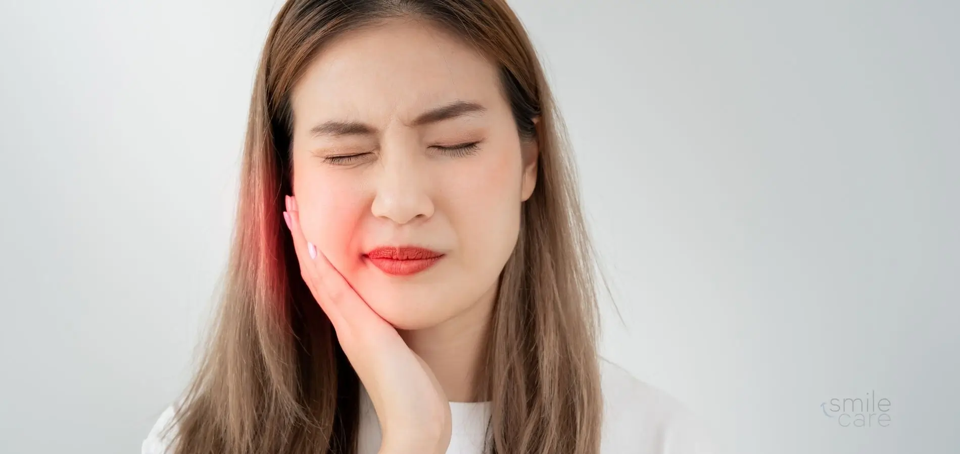 Mujer se toca la cara por dolor de muelas: una de las senales de que neceistas una endodoncia